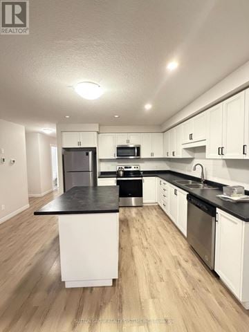 Norfolk (Simcoe) townhouse for rent - A modern kitchen with white cabinets and a black countertop.