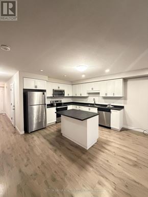 Norfolk (Simcoe) townhouse for rent - A modern kitchen with white cabinets and a central island.