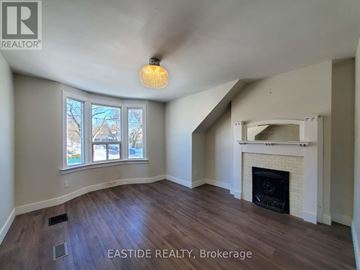 Toronto (Danforth) house for rent - A room with a fireplace and a window with a view of trees.