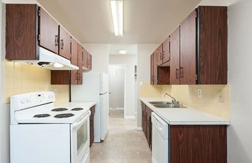 Edmonton apartment for rent - A kitchen with white appliances and wooden cabinets.