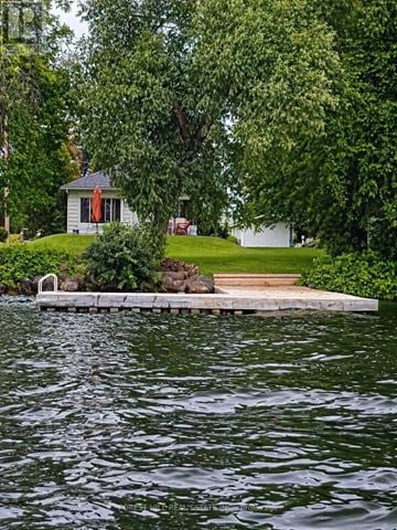 Innisfil house for rent - A house is situated by a body of water with a dock leading to it.