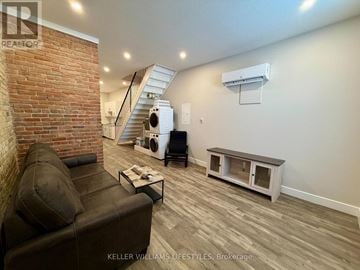 St. Thomas multi-family for rent - A living room with a brown leather couch and a brick wall.