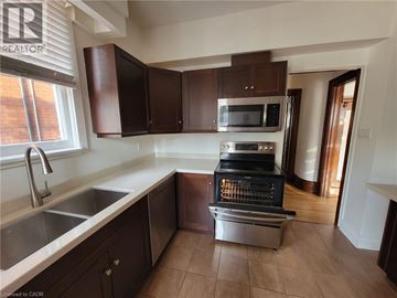 Hamilton house for rent - A kitchen with brown cabinets and a stainless steel oven.
