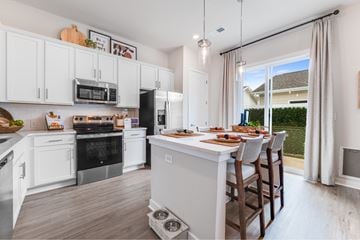 Monroe townhouse for rent - A kitchen with white cabinets and a large island with chairs around it.