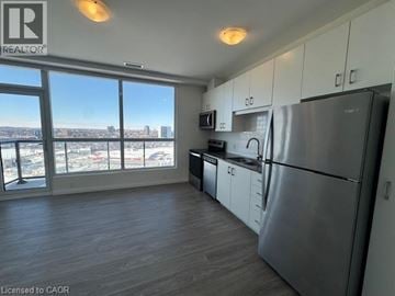 Kitchener condo for rent - A kitchen with white cabinets and a black fridge.