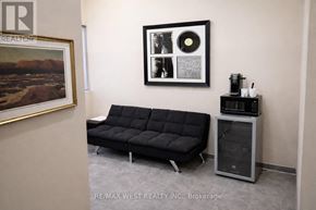 For rent in Toronto (Weston) - A black sofa sits in a room with a framed picture and a record player.