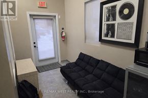 For rent in Toronto (Weston) - A brokerage office with a black couch and a framed record on the wall.