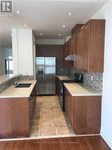 Mississauga (Hurontario) house for rent - A kitchen with brown cabinets and a marble backsplash.