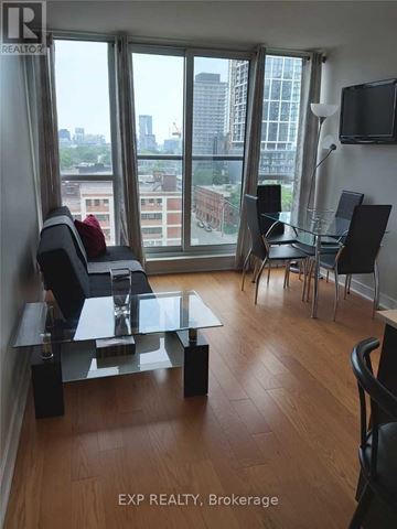 Toronto (Moss Park) condo for rent - A living room with a glass table and chairs with a view of the city.