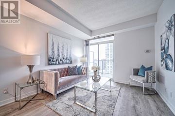Toronto (Tam O'shanter-Sullivan) condo for rent - A living room with a couch, a glass table, and a painting on the wall.