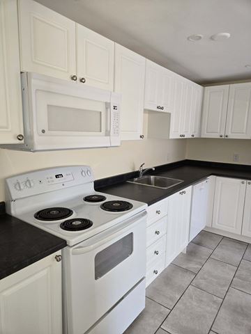 Halifax apartment for rent - A white stove and microwave in a kitchen with white cabinets.