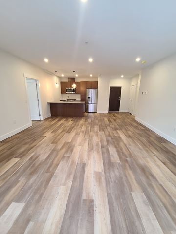 Halifax apartment for rent - A spacious room with wooden flooring and a kitchen area in the background.
