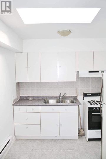 Toronto (East End-Danforth) other for rent - A white kitchen with a sink, stove, and cabinets.