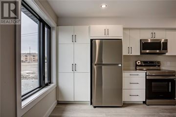 Azilda apartment for rent - A modern kitchen with a stainless steel refrigerator and white cabinets.