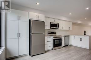 Azilda apartment for rent - A modern kitchen with white cabinets and stainless steel appliances.