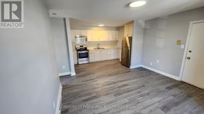 Toronto (Caledonia-Fairbank) multi-family for rent - A well-lit kitchen with wooden flooring and white walls.