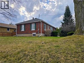 Cambridge house for rent - A house with a red brick exterior and a white window is surrounded by a grassy yard.