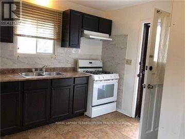 Toronto (Scarborough Village) house for rent - A kitchen with black cabinets and a white stove.