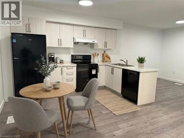Welland townhouse for rent - A modern kitchen with a black fridge, black oven, and a wooden table with two grey chairs.