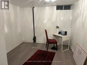 Whitchurch-Stouffville (Stouffville) house for rent - A room with a red chair and a desk with a white chair and a sign that says RE/MAX HALLMARK REALTY LTD Brokerage.