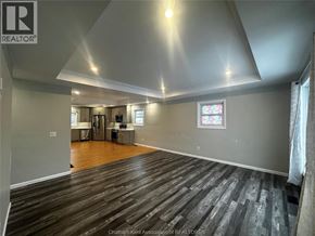 Merlin house for rent - A spacious room with wooden flooring and a stained glass window.