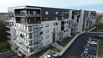 Moncton apartment for rent - A modern apartment building with a parking lot in front.