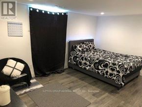 Toronto (Wexford-Maryvale) house for rent - A bedroom with a black and white bed and a black chair.