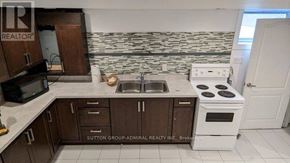 Toronto (Wexford-Maryvale) house for rent - A kitchen with a white stove and brown cabinets.