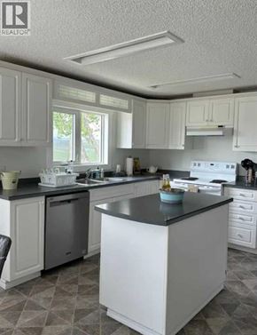 For rent in Rural Cardston County - A kitchen with white cabinets and a black countertop.