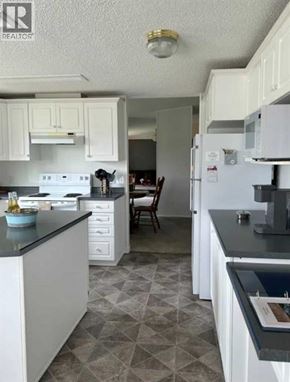 For rent in Rural Cardston County - A kitchen with white cabinets and a black counter top.