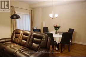 Kitchener townhouse for rent - A brown leather couch sits in a room with a dining table and chairs.