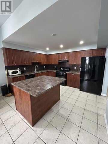 Brampton (Northwest Brampton) townhouse for rent - A kitchen with a black refrigerator and brown cabinets.