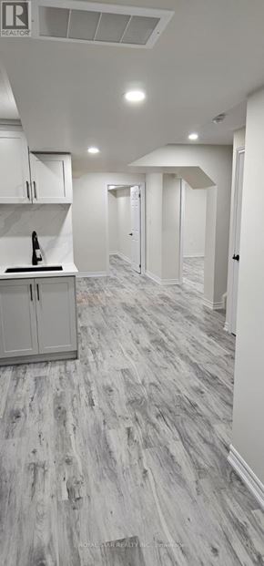Oshawa (Eastdale) house for rent - A kitchen with white cabinets and a wooden floor.