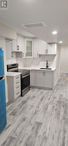 Oshawa (Eastdale) house for rent - A kitchen with white cabinets and a grey floor.