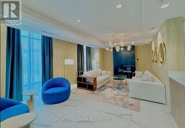 Whitby (Pringle Creek) condo for rent - A spacious living room with a blue chair and a white couch.