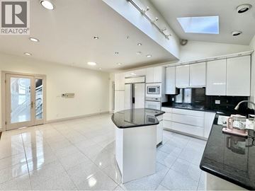 Vancouver house for rent - A modern kitchen with white cabinets and black countertops.