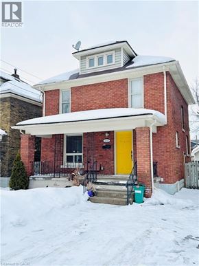 Niagara Falls house for rent - A red brick house with a yellow door and a white awning.