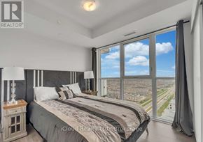 Oshawa (Windfields) condo for rent - A bedroom with a large bed and a view of the city.