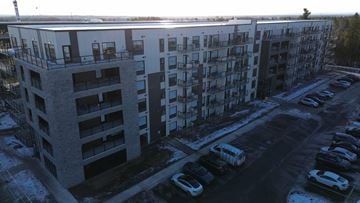 Moncton apartment for rent - A large apartment building with a parking lot in front.