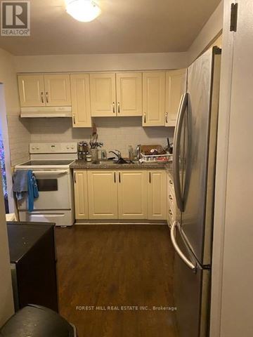 Toronto (Kensington-Chinatown) condo for rent - A kitchen with wooden cabinets and a white fridge.