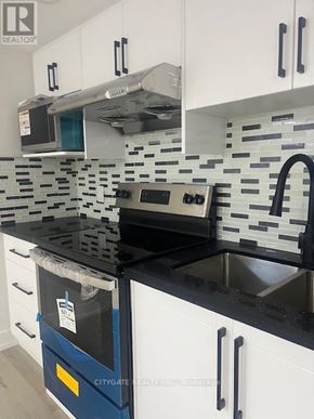 Toronto (Cliffcrest) house for rent - A kitchen with black countertops and white cabinets.