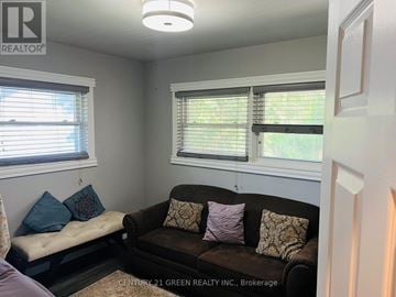 Halton Hills (Rural Halton Hills) house for rent - A living room with a brown couch and a window with blinds.