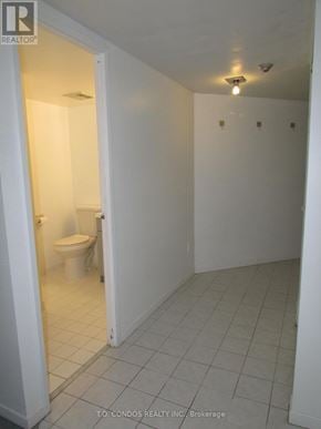 Toronto (Bay Street Corridor) condo for rent - A white bathroom with a toilet and a doorway leading to another room.