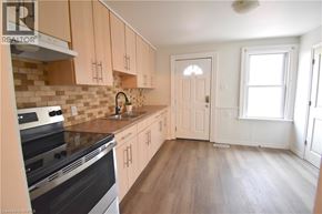 Brantford house for rent - A kitchen with wooden cabinets and a black stove top oven.
