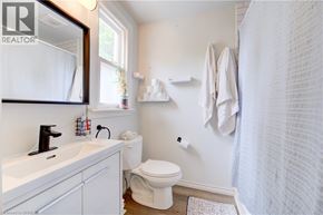 Brantford house for rent - A white bathroom with a toilet, sink, and shower curtain.