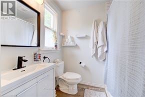 Brantford house for rent - A white bathroom with a toilet, sink, and shower curtain.