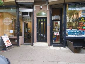 New York apartment for rent - the front door of a store with a sale sign on the sidewalk