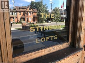 Hamilton condo for rent - A window with a reflection of a building and the words "The Stinson Lofts" written on it.