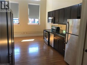 Hamilton condo for rent - A kitchen with black cabinets and a refrigerator.