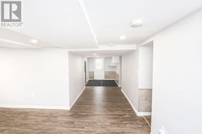 Prince Edward County (Picton Ward) duplex for rent - A spacious room with wooden flooring and white walls.